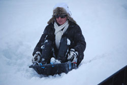 Adult racing downhill in an EcoSledge sledge