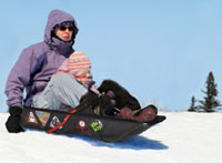 Adult and child sledging down hill